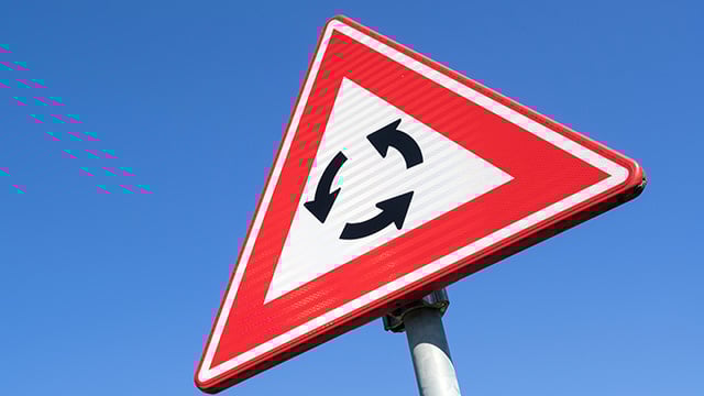 Roundabout sign against a blue sky